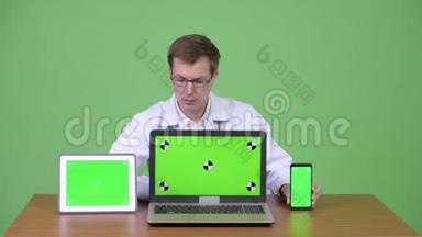 医生端坐及显示彩色钥匙绿色屏幕笔记本电脑数码平板电脑及手机